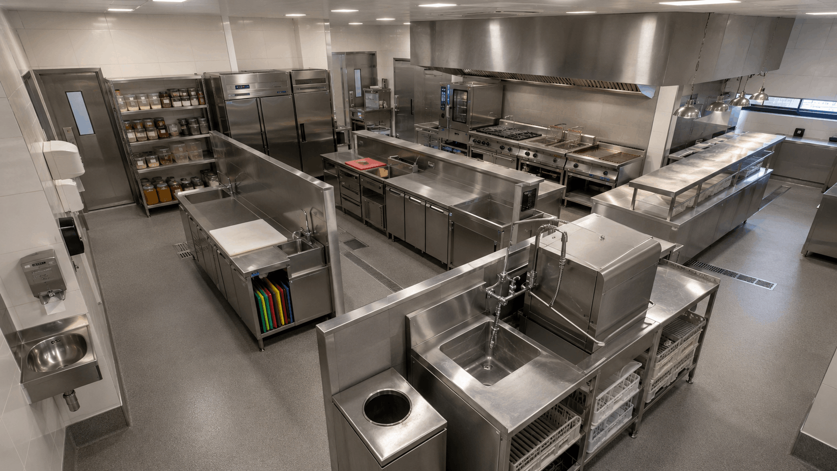 Overhead view of a zoned commercial kitchen showing dry storage shelving, a central cooking line, and a dedicated dishwashing station